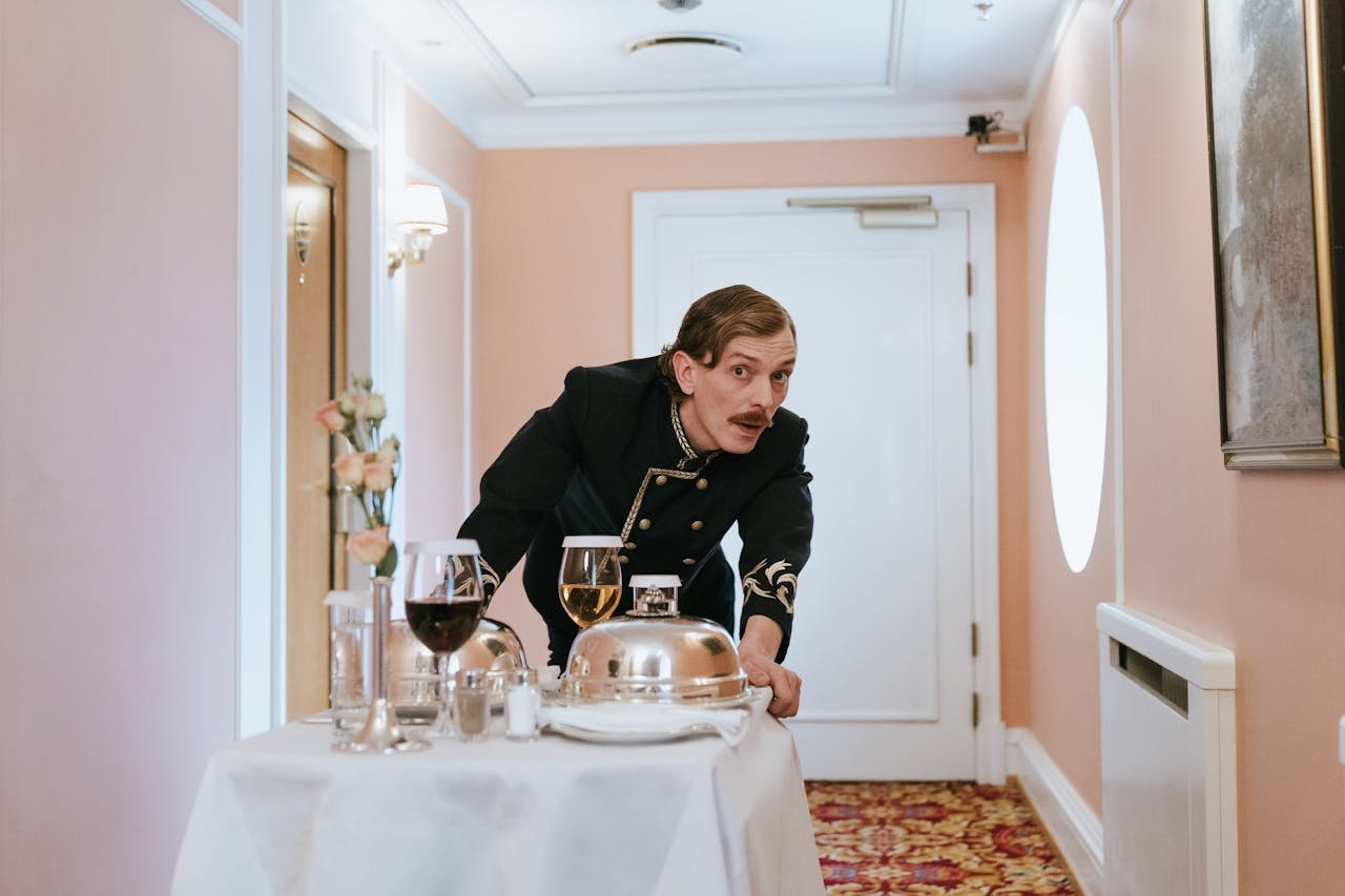 Hotel staff member in uniform serving room service in a luxurious corridor.