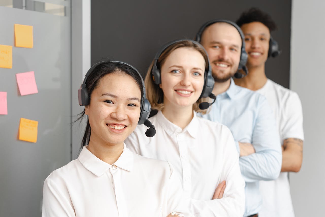 Smiling customer service team wearing headsets in an office setting, ready to assist clients.